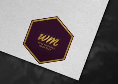 Hexagon logo design for West Michigan Prop Shop featuring plum and gold color palette